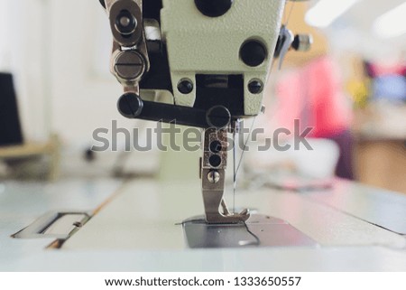 Professional sewing machine on the background of atelier studio. Workplace of tailor - sewing machine, rolls of thread, fabric, scissors. Sewing business concept.