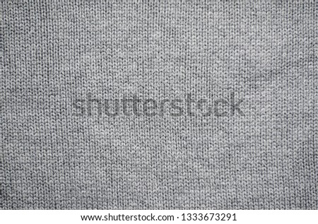 Knitted fabric background. The texture of grey woolen fabric. 