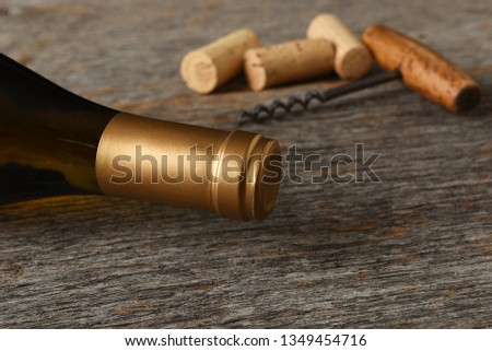 White Wine Still Life: Closeup of a bottle of Chardonnay wine with corkscrew and corks on a rustic wood table.