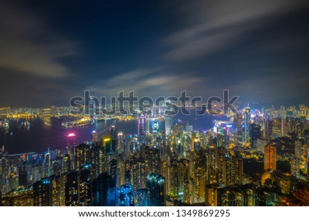 Aerial Skyline Cityscape and Light Trail from Ferry Boats Traffic of Victoria Bay with Countless Skyscrapers shot from Victoria Peak at Night Time in Never Sleep City Hong Kong.