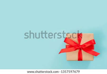 Gift box or present wrapped with red bow on blue background. Top view, flat lay
