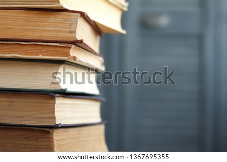 A stack of vintage books for business and education on a wooden surface against a white wall, back to school concept.