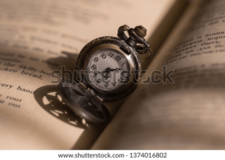 A pocket watch on the book’s page