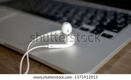 Laptop with white earphones on office table background