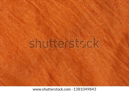 Texture of orange fabric. Texture t is light brown textile material. Auburn scarf closeup. Dark Yellow Palatine.