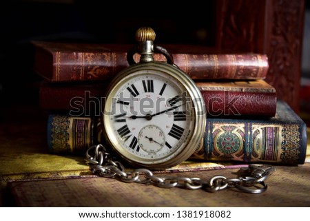 Very old pocket watch and books on a table