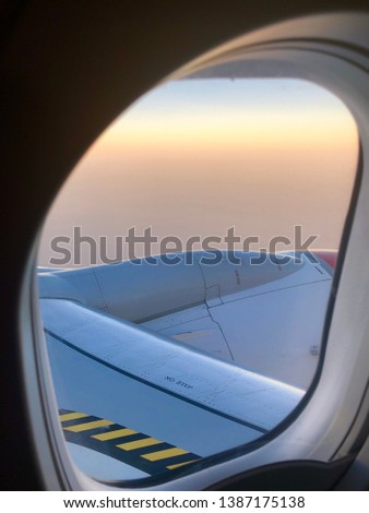 View of wing outside the airplane aeroplane window at sunset above the clouds
