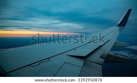 View out of the window from a commercial airplane of the wing with a beautiful sunset out on the horizon.