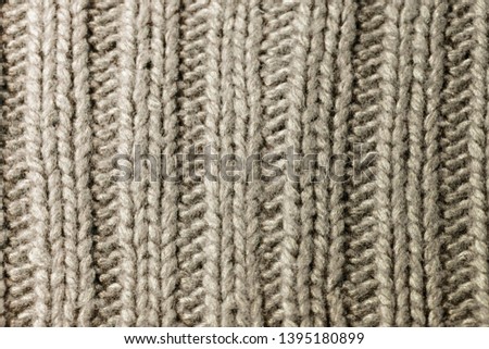 Background texture of greige or gray and beige rib or cable stitch pattern knitted fabric made of cotton or wool. closeup.