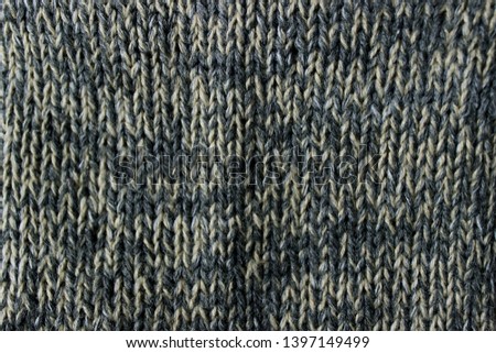 Knitted fabric of two colors, beige and earrings. Horizontal photo, macro.
