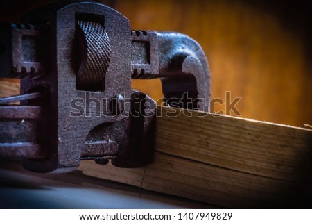 Rusted, stained pipe wrench hand tool clamped with a wooden block