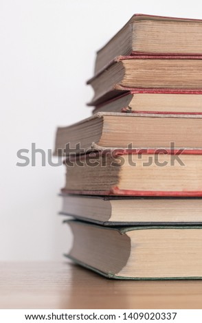 Pile of old dusty books on a wooden surface