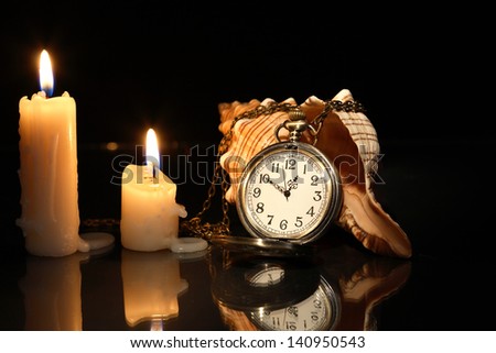 Vintage pocket watch near lighting candles and shell