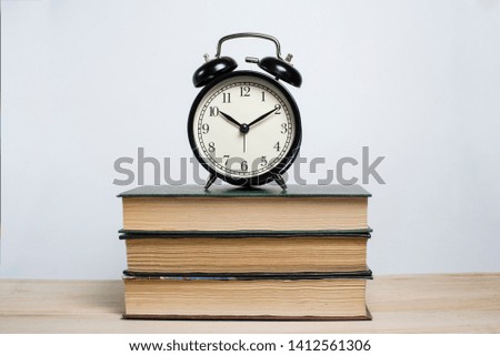 Retro alarm clock on a stack of books on a wooden table on a white background. Studying at school and university. Good morning. Deadline.