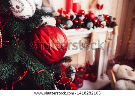 Christmas interior with fireplace.Red and golden balls and illuminated garland with flashlights.New Year baubles macro photo with bokeh. Winter holiday light decoration.sparkling and fairy background