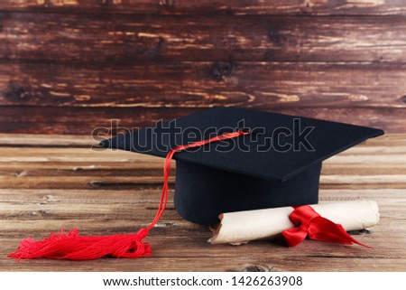 Graduation cap with diploma on brown wooden table