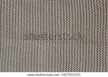 
The texture of warm clothing for the autumn and winter season. Gray umber color knitted fabric. Machine binding. Close-up.