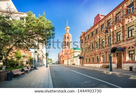 The bell tower of the Petrovsky Monastery in Moscow and benches under the trees on a sunny summer morning