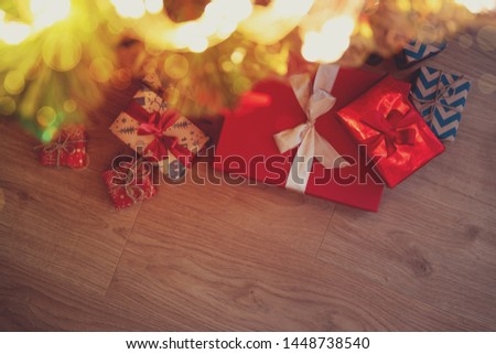 Christmas gift boxes wrapped red ribbon lying on Christmas tree against lights background. Christmas or New Year celebration concept. Copy space. Selective focus