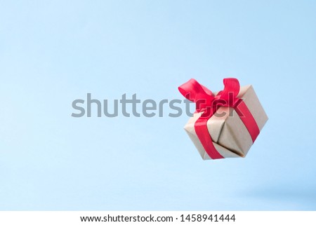 Gift box with red ribbon on blue background. zero gravity. levitation. milimalism. copyspace. Concept sales, shopping, christmas holidays and birthday.