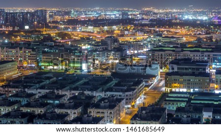 Aerial view of neighbourhood Deira and Dubai creek with typical old and modern buildings night timelapse. Airport on a background. View from skyscraper rooftop. Dubai, United Arab Emirates