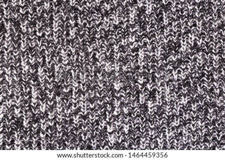 Background from a fabric texture. Wool knitted fabric with cable seamless pattern of white black color. Textil closeup.Concept of example, learning of knitting,concept of cover,notebooks, decoration.