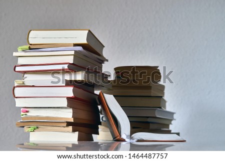 A pile, a pack of books and one book is opened, the ends of the books are background.  