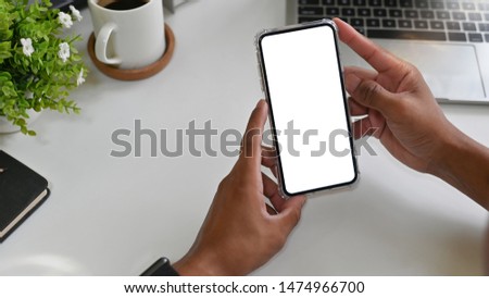 Hands using mockup smartphone on office desk.