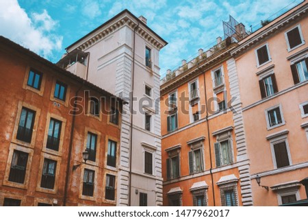 Ancient building in Rome, Italy. Windows with shutters, sky over the city. The sky is reflected in the windows. Italian cityscape. Sunny day in Rome. 