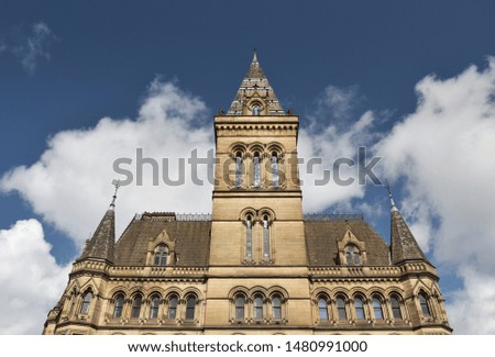 Looking up at an old building against a dramatic blue sky with white clouds. Taken in Manchester England.