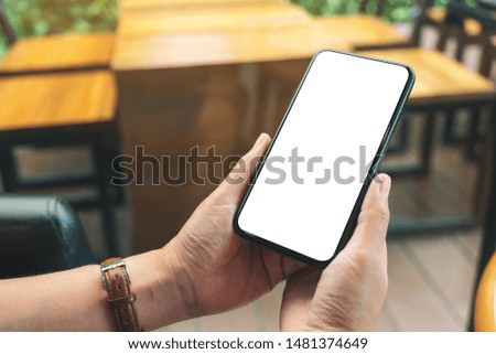 Mockup image of hands holding black mobile phone with blank desktop screen