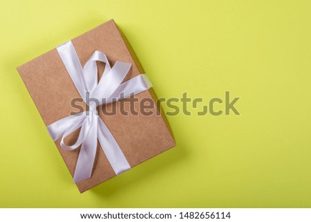 Gift box with bow on green neon background. Space for text on the right side of the image.