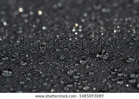 dark gray waterproof hydrophobic flat cloth closeup with rain drops selective focus background