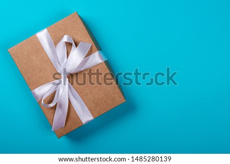 Gift box with bow on neon blue background. Space for text on the right side of the image.