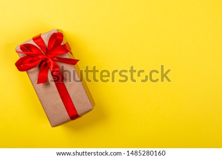 Gift box with bow on yellow background. Space for text on the right side of the image.