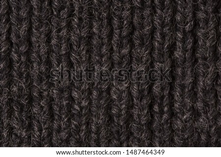 The texture of the knitted fabric is gray-black. Background, backdrop, top view.