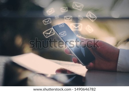 Side view and close up of hand using smartphone with glowing email network on blurry background. E-mail marketing, message and communication concept. Multiexposure 