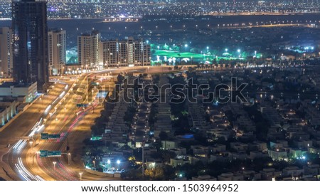 Aerial view of apartment houses and villas in Dubai city night timelapse near jumeirah lake towers district, United Arab Emirates. Top fiew from skyscraper with traffic on highway