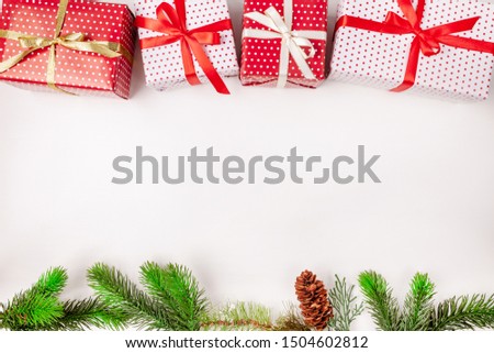 Christmas gift boxes with ribbons, fir tree branches and cone on white background. Copy space. Top view.