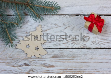 Flatlay greeting card with space for your text. Fluffy fir branch, wooden Christmas tree and Santa Claus oi gift on a light wooden table.
