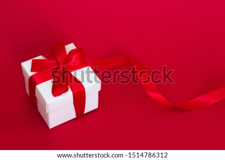 White box with a red ribbon on a red background. Greeting card concept