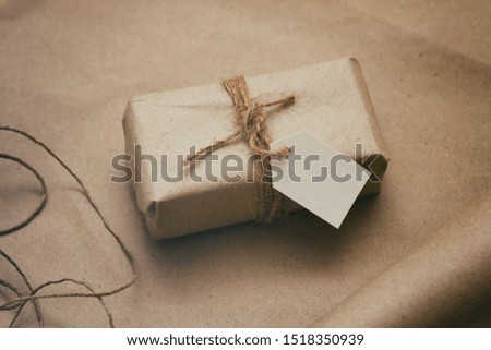 Parcel wrapping in brown craft paper and tie hemp string. Package with paper label. Delivery service. Online shopping. Your purchase. Gift box on a table. Hemp threads. 