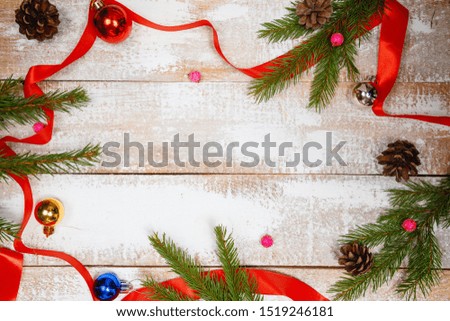 On a wooden vintage white background lie spruce branches and cones with a ribbon. Blank for Christmas card on a wooden background
