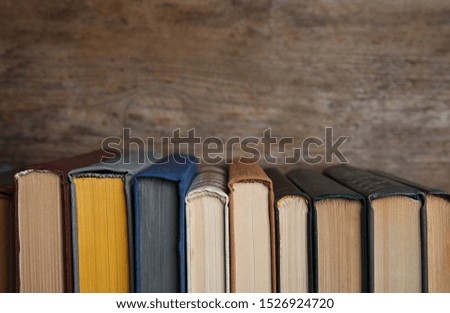 Stack of hardcover books on wooden background. Space for text