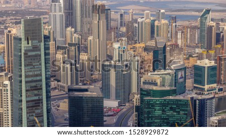Panoramic aerial view of business bay towers and downtown in Dubai at evening timelapse. Rooftop view of some skyscrapers, canal and new towers under construction.