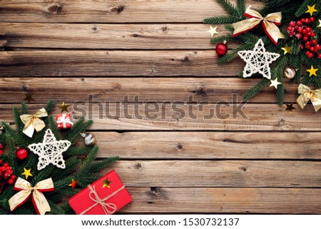 Christmas tree branches with toys and gift box on brown wooden table