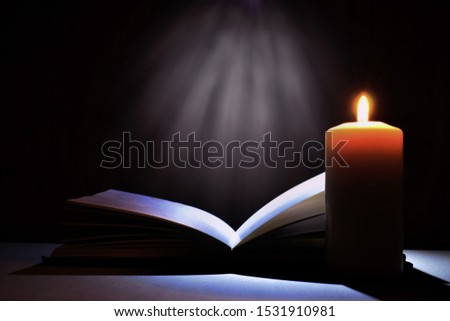 Magic book and candle. Bible book and mysterious light. The voice of God. Prayer to God. Religious concept. Secret book.