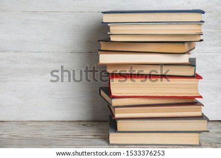Stack of hardcover books on wooden table against white background. Space for text
