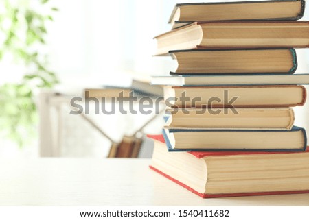 Stack of hardcover books on white wooden table indoors. Space for text
