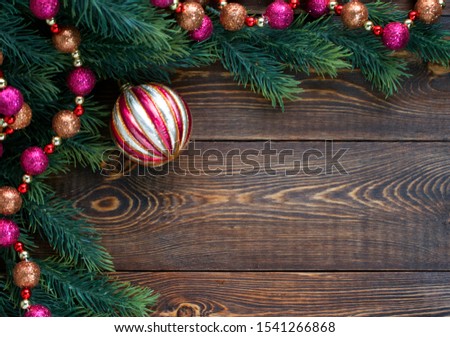 Christmas composition. Frame of fir branches, pink and orange Christmas tree balls on wooden brown background. Christmas, winter, New Year concept. Flat lay, top view, copy space